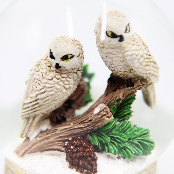 snowy owl pair sitting on a branch together in a birch based snow globe, close up