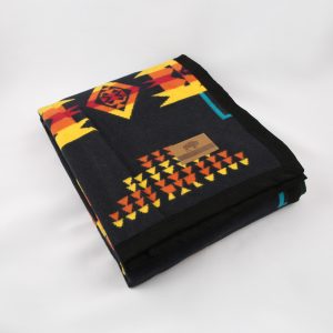 A black blanket with gold and yellow indigenous patterns on it.
