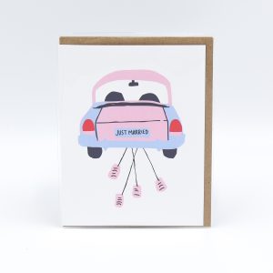 A wedding card with an illustration of a pink car with a just married sign on it. The car is dragging cans behind it.