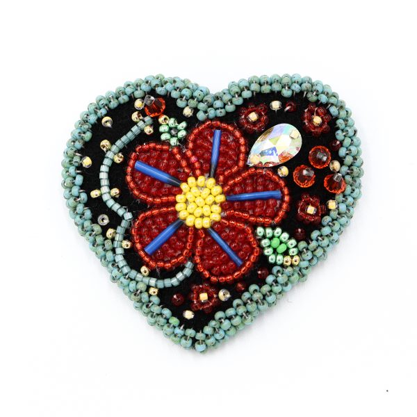 beaded heart brooch with blue border and red flower, it is a photo of the brooch for display purposes.