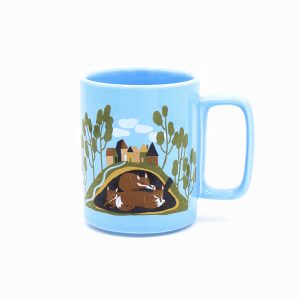 Blue stonewear mug with square handle and painted with images of burrowing animals in a burrow, one side is badgers the other is foxes.