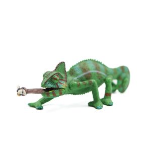 A small plastic figurine of a chameleon with its tongue out catching a bug.