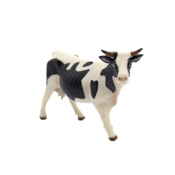 A photo of a plastic cow figurine shot against a white background.