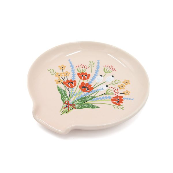 Pink circular spoon rest with an image of a colourful bouquet on it and a small flat opening.