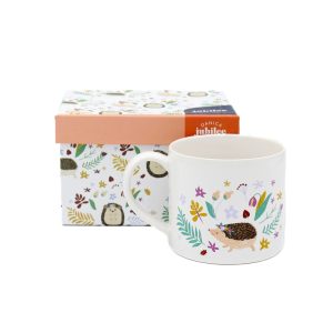 A small white stonewear mug photographed with its box in front of a white background, and is patterned with hedge hogs and flowers.
