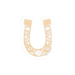 white background with a light orangey brown horseshoe sticker on it. It has white designs of flowers on it in a pattern.