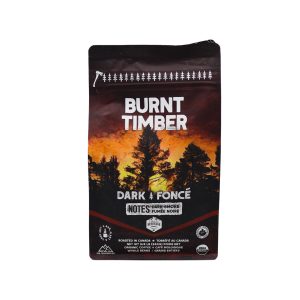 A brown, 340 gram tetra-pack of dark roast coffee beans with a burning forest in the background.