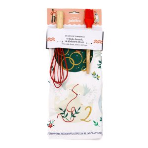 whisk, brush, and dishtowel inside their packaging. The dishtowel is mostly white, the whisk is red, the brush is also red.