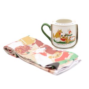 white mug with a green handle and a pack of pups waiting for santa on it as the design. The tea towel is similarly patterned.